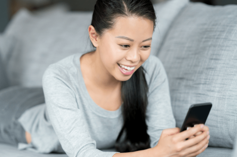 Filipino Woman at Home Using a Dating App on Her Cellphone