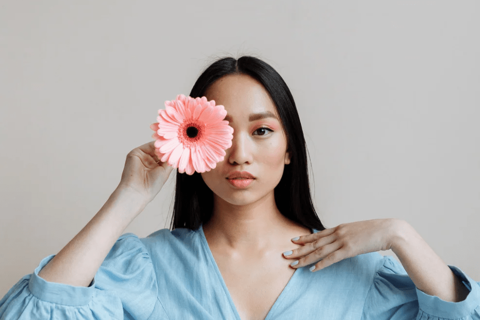 Filipina Holding a Daisy Covering Her Right Eye - Common Misconceptions about Dating Filipino Women - Blossoms Dating Blog