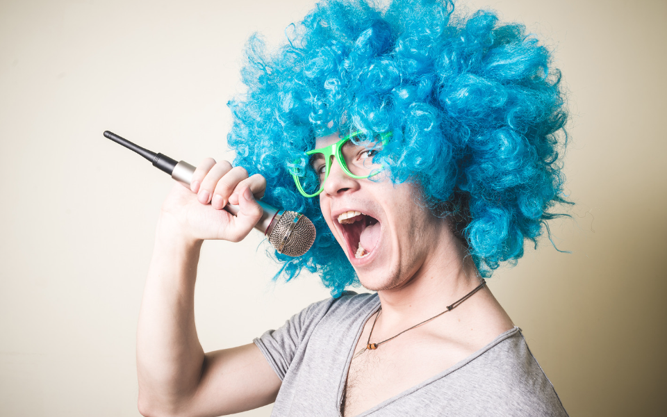 Funny Man Wearing a Blue Wig While Holding a Microphone