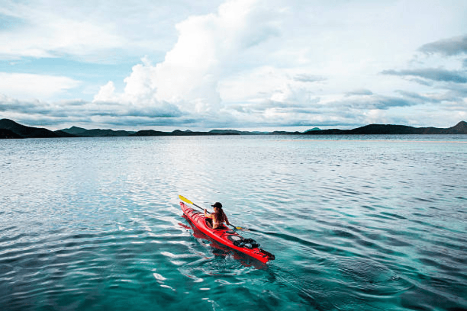 A Filipino Woman Paddling a Red Kayak Near Sunset in the Philippines - The Do's and Don'ts of Dating a Filipino Woman - Blossoms Dating Blog