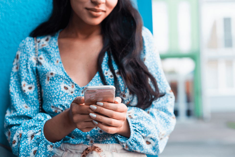 Filipino Woman with Long Hair Using Her Phone - Signs a Filipina Likes You - Blossoms Dating Blog