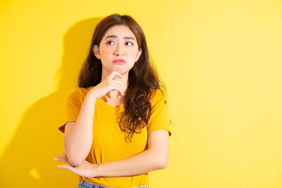 Jealous Filipino Woman Posing on Against a Yellow Background - The Pros and Cons of Dating a Filipino Woman - Blossoms Dating Blog