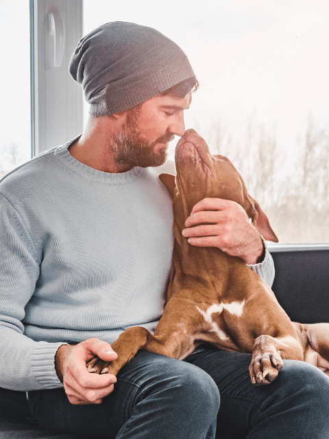 Man Cuddling with a Puppy on the Couch - The Top Traits Filipino Women Look for in a Partner - Blossoms Dating Blog