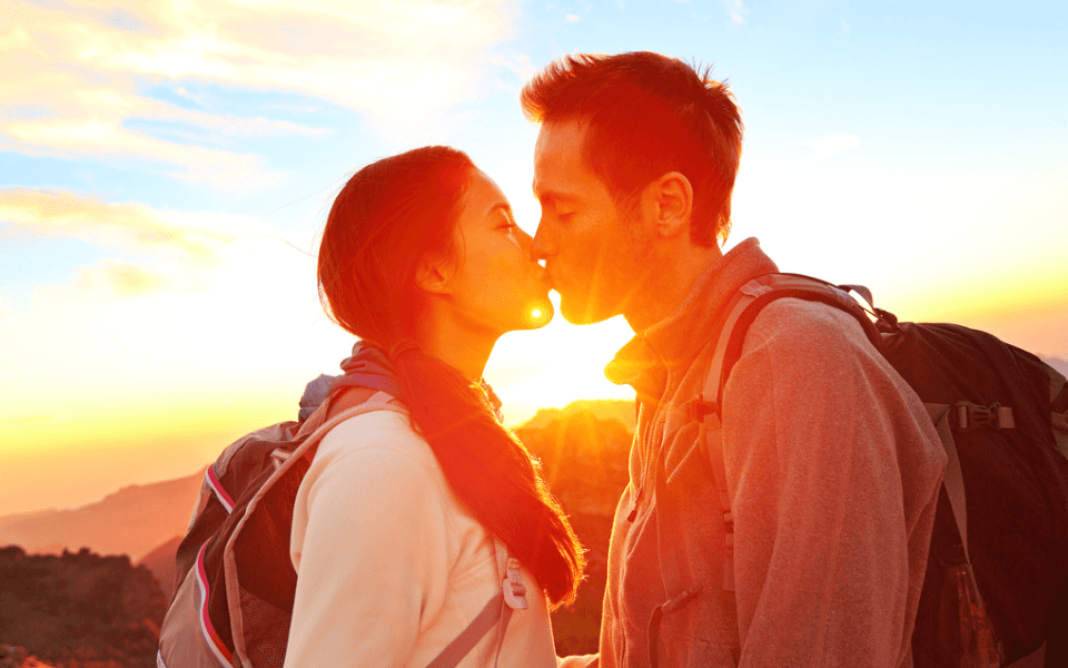 Romantic Lovers Kissing at Sunset While Hiking on a Date