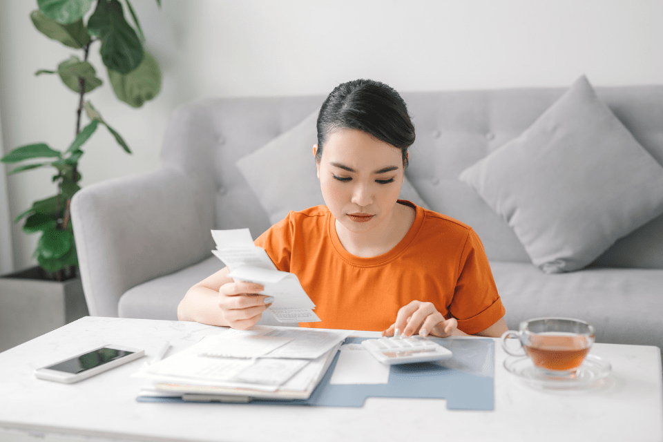 Sad Filipina in the Living Room Calculating Monthly Living Expenses