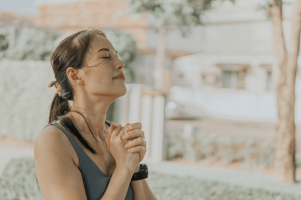 Christian Filipino woman praying outdoors.