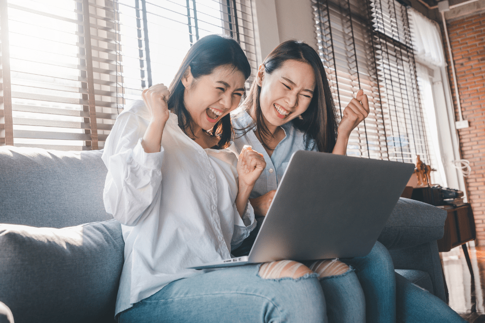 Happy Christian Filipina best friends using the laptop at home.
