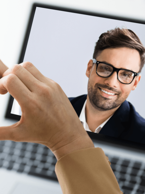 Online video call on laptop computer with the woman making a small gesture (heart)