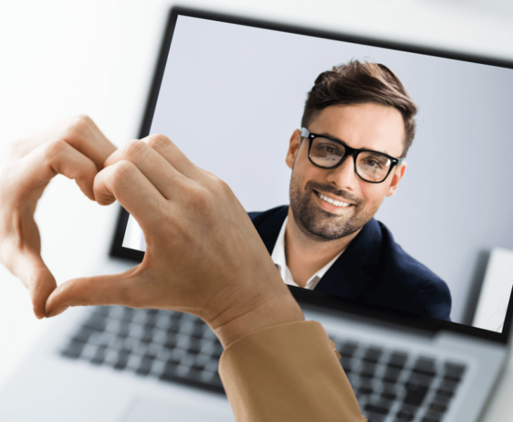 Online video call on laptop computer with the woman making a small gesture (heart)