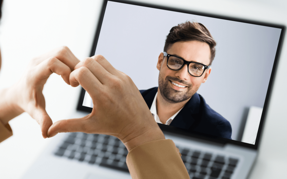 Online video call on laptop computer with the woman making a small gesture (heart)