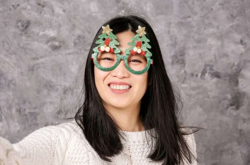 A Filipina woman wearing festive Christmas eyewear and smiling brightly.