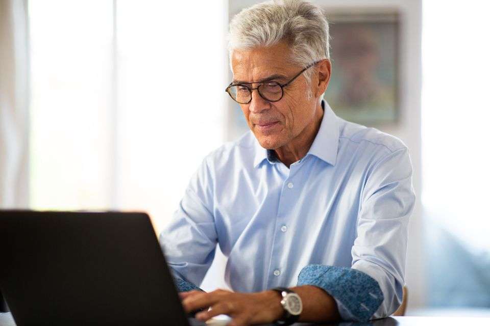 A Mature Man Using His Laptop to Chat with His Online Date at Blossoms Dating